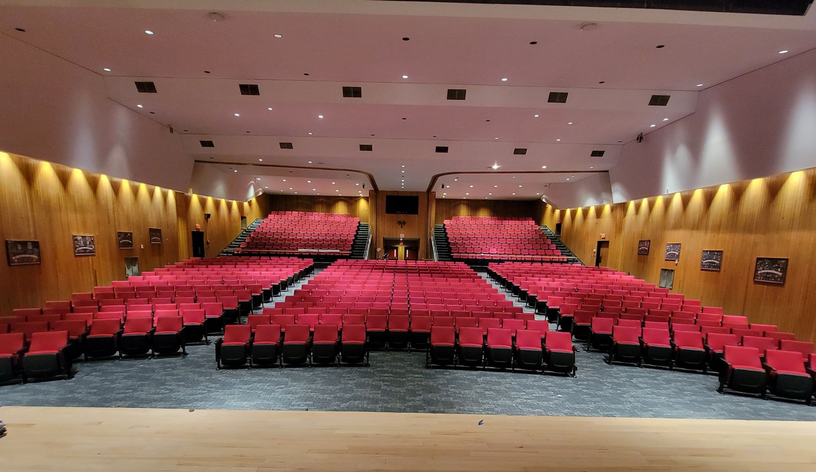 Wood-paneled auditorium filled with new red fixed seating, viewed from the stage