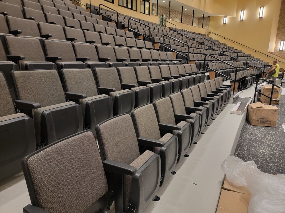 Rows of charcoal upholstered auditorium seats along a steep aisle