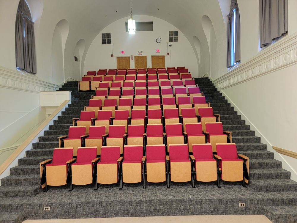 Historic campus auditorium with new red and wood fixed seating