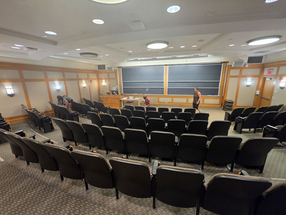 Lecture hall with black fixed seats facing chalkboards