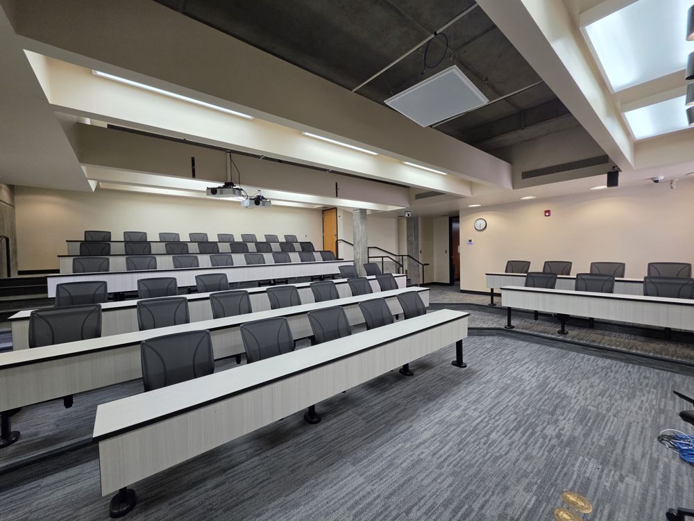 Side view of a tiered lecture hall with tables and seats