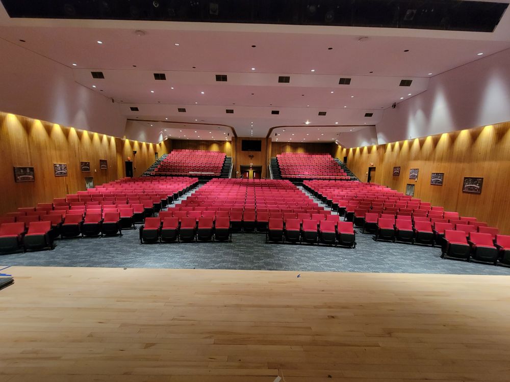 Wood-paneled auditorium filled with red upholstered seats